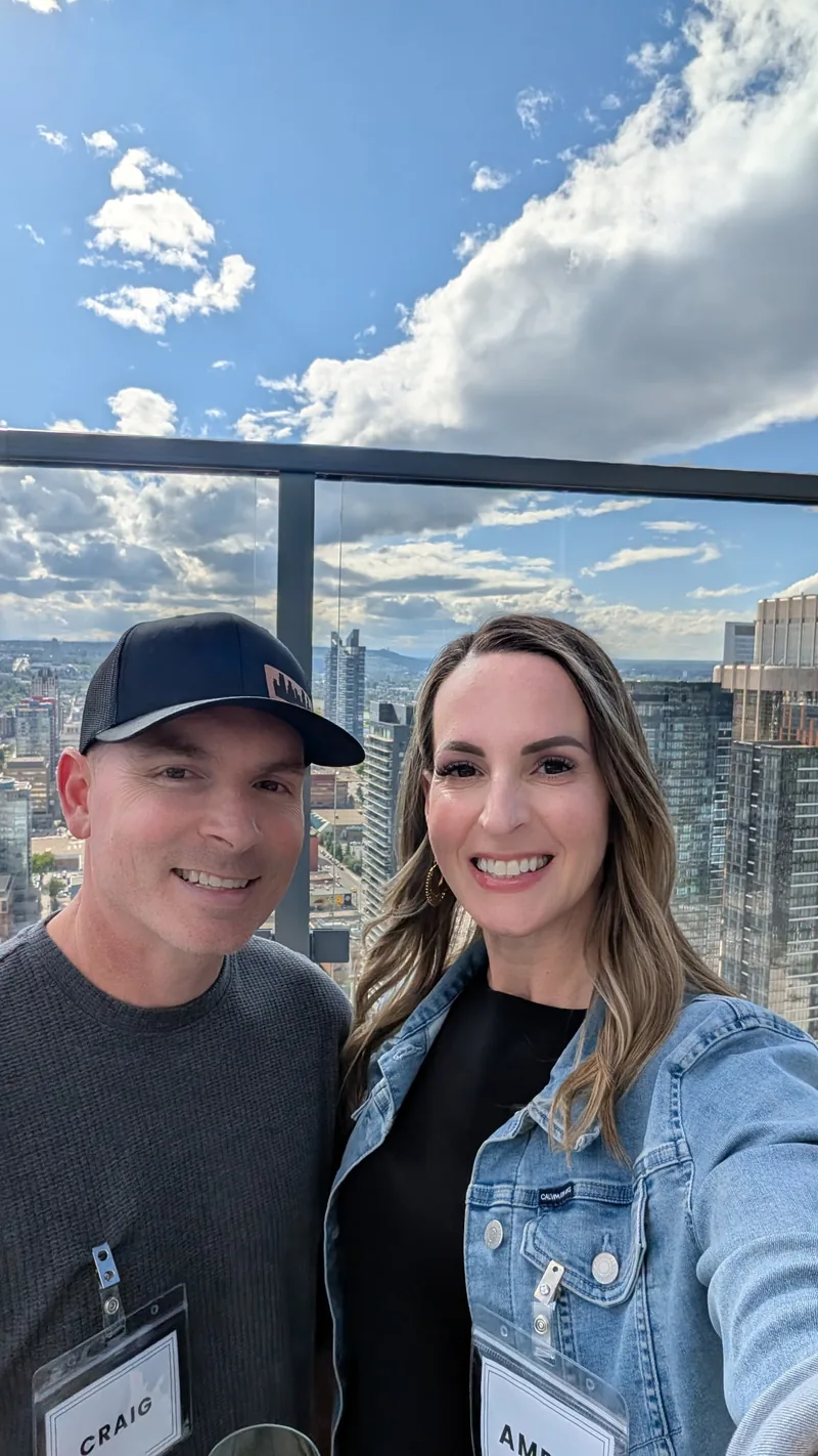 Craig and Amber DeMaere at a Calgary investor event, downtown skyline behind them